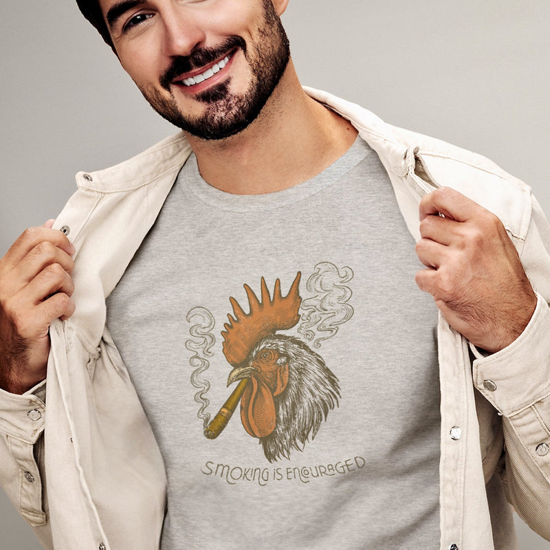 PRODUCT IMAGE: Smokin’ Cock Tee  | Funny, Raunchy T-shirt for Horny Gay Men | Model wears Light Gray Heather shirt with a vintage-style graphic of a rooster smoking a cigar