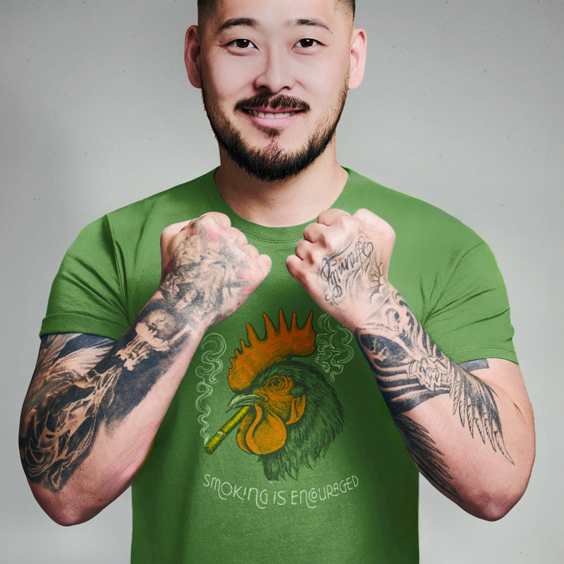 PRODUCT IMAGE: Smokin’ Cock Tee  | Funny, Raunchy T-shirt for Horny Gay Men | Model wears Leaf green shirt with a vintage-style graphic of a rooster smoking a cigar