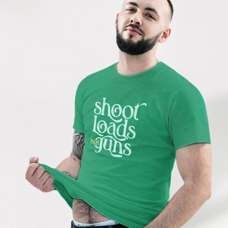 PRODUCT IMAGE: Model wears Kelly Green tee with typographic design, "Shoot Loads Not Guns" | Conscious and Raunchy T-shirt for Guys into Cum