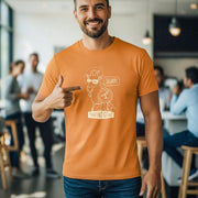 A man wearing an orange graphic t-shirt with a cartoon character and the words 'SLURP!' and 'THROAT GOAT!' pointing to the chest graphic, set in a blurred cafe environment.