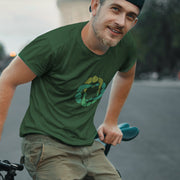 Model wears forest green cotton t-shirt with subtle circle graphic of seated male figures holding hands (Circle Jerks), viewed from above; gay-themed design for bators and group play