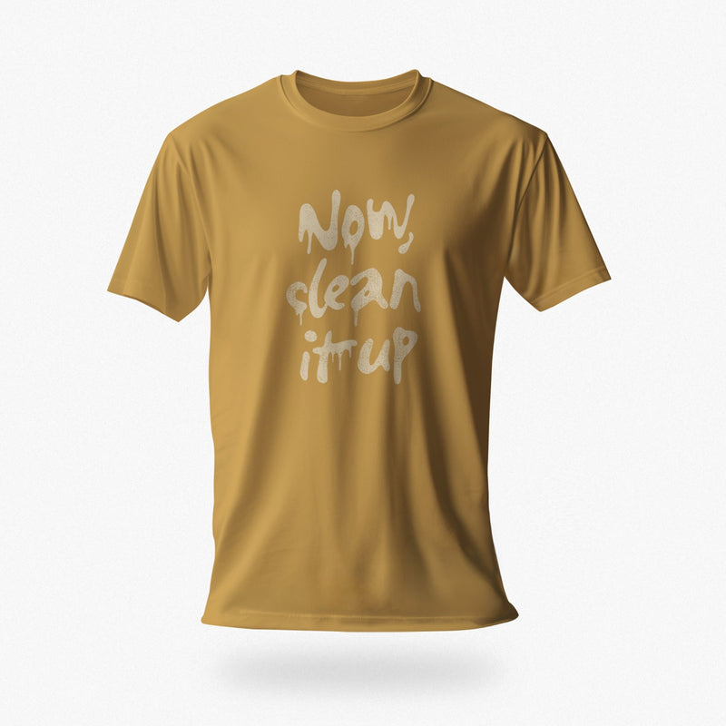 Product image of the mustard color t-shirt with "Now, clean it up" printed on the chest; the  milky white letterforms drip, lending to an appropriate interpretation