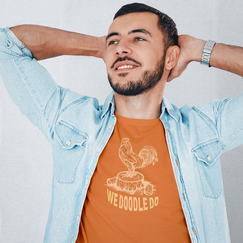 A model wears the orange Cock We Doodle Do T-shirt | SFW Homo Erotic Tee for Horny Gay Men | His hands behind his head, he kicks back with a smile as looks off to the left