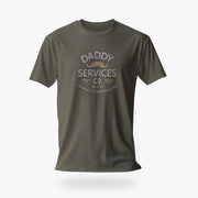 An olive green short-sleeve t-shirt with a vintage-style graphic on the chest reading 'DADDY SERVICES CO' in white and gold, featuring a small mustache illustration, shown against a light gray background.