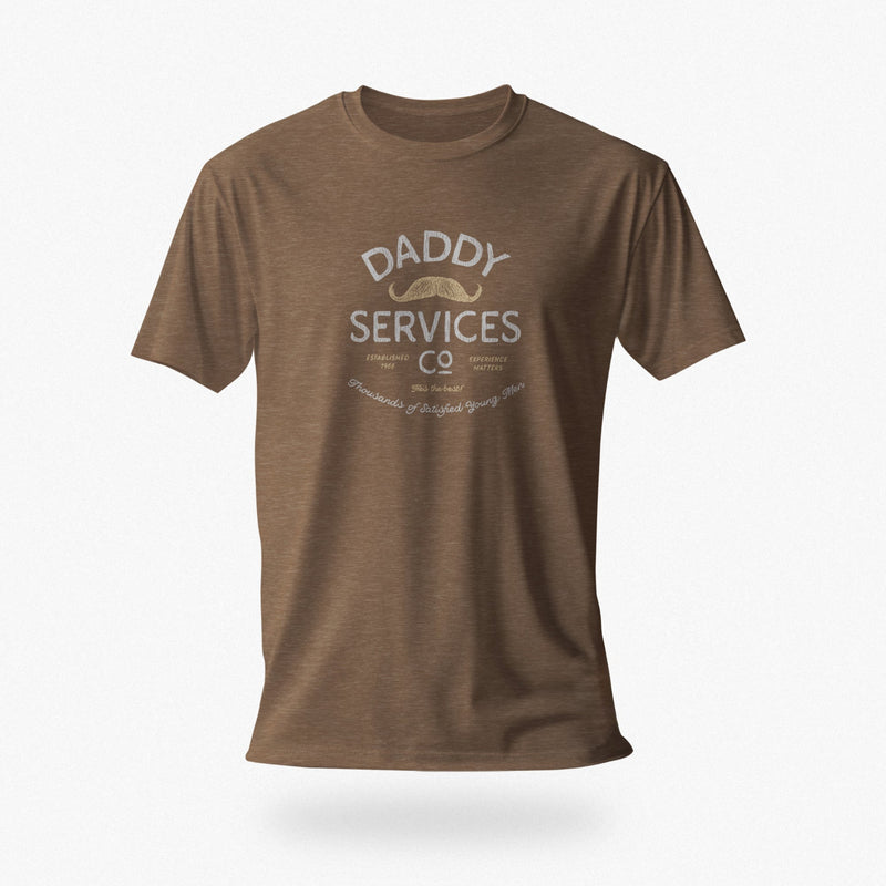 A brown short-sleeve crewneck t-shirt with a vintage-style graphic on the chest reading 'DADDY SERVICES CO' with a small mustache illustration, shown against a light gray background.