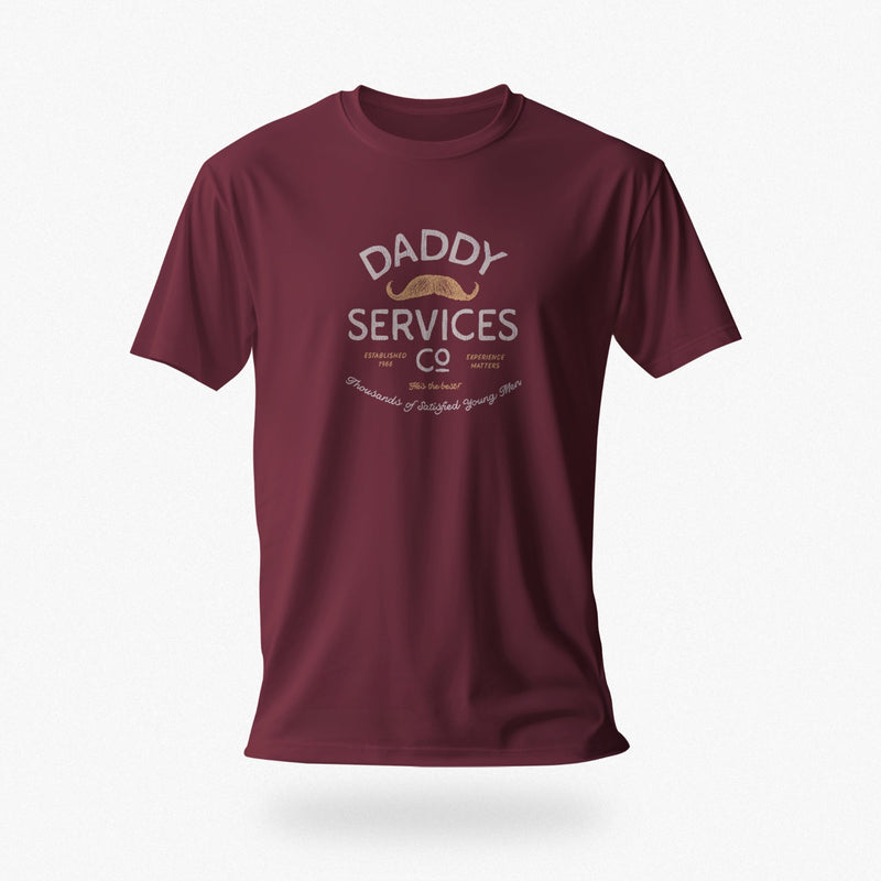 A maroon short-sleeve t-shirt with a vintage-style graphic on the chest reading 'DADDY SERVICES CO' in cream and gold, displayed against a clean white background.