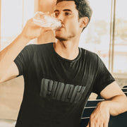 PRODUCT IMAGE: Fuck | Offensive NSFW T-shirt for Horny Gay Guys | Typographic Design | Model w/ Black tee with typographic design