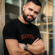 A bearded man wearing a navy t-shirt with the word 'GIRTH' printed in capital letters on the front.