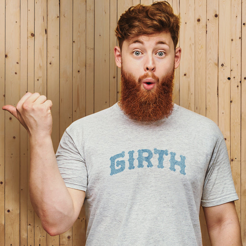 PRODUCT IMAGE: Girth | Homo Erotic T-shirts Celebrating Thickness: Cocks & Gay Bears | Redhead model with a beard wears Light Gray Heather shirt with neo-gothic Typographic design