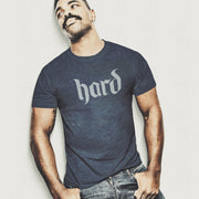 PRODUCT IMAGE: Hard T-Shirt | Raunchy Graphic Tee for Horny Gay Men into big boners, hard cocks, and erections | Model wears Heather Navy shirt with a design created with blackletter / gothic typography