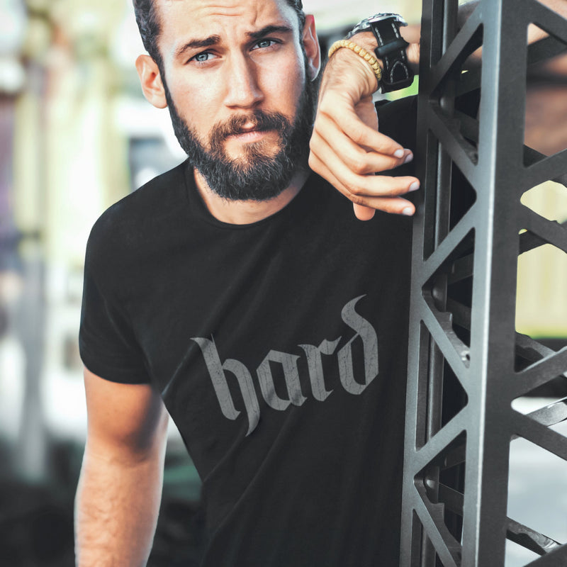 PRODUCT IMAGE: Hard T-Shirt | Raunchy Graphic Tee for Horny Gay Men into big boners, hard cocks, and erctions | Model wears Vintage Black shirt with a design created with blackletter / gothic typography