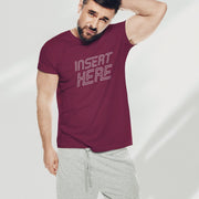 PRODUCT IMAGE: 'Insert Here' T-shirt | Suggestively raunchy tee for horny gay bottom guys | An inviting handsome male model stands with his left arm over his head, wears a Maroon tee with a white distressed typographic design is printed on it, in the chest area 