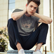 Model wears Charcoal shirt with a woodcut-style linedrawing of a pink pig with typography below, revealing the design's name, "This ‘Lil Piggy T-shirt"; Funny Gay SFW Tee for Horny Gay Guys Who are Quietly Nasty Pigs