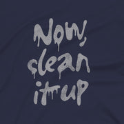 Close up of a navy t-shirt with "Now, clean it up" printed on the chest; the  milky white letterforms drip, lending to an appropriate interpretation