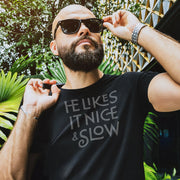 PRODUCT IMAGE: He Likes It Nice & Slow T-shirt | Funny Gay Tee for the guys who take their time and enjoy the ride | Model wears Black shirt with a design borne out of retro-inspired typography