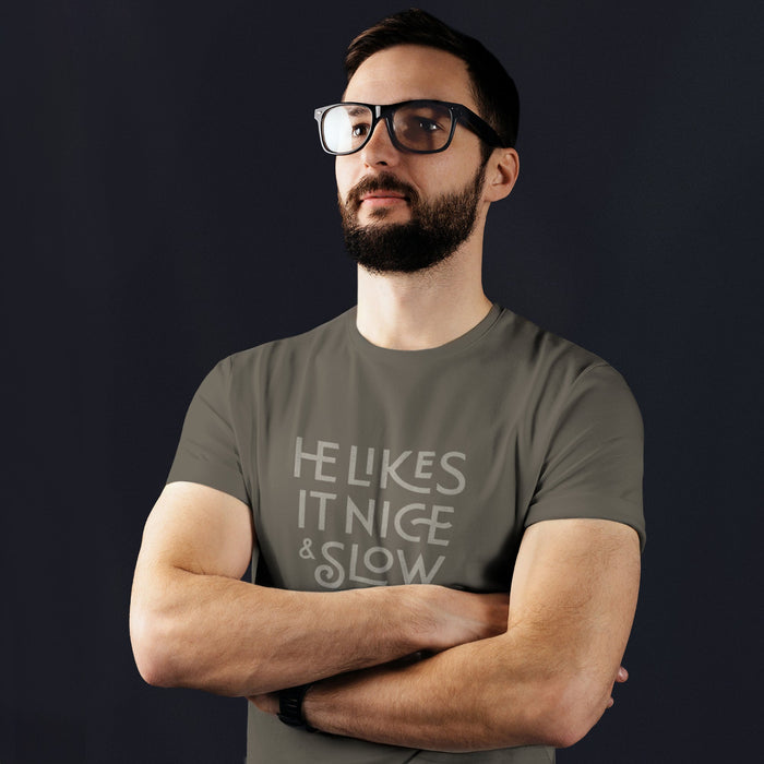 PRODUCT IMAGE: He Likes It Nice & Slow T-shirt | Funny Gay Tee for the guys who take their time and enjoy the ride | Model wears Charcoal shirt with a design borne out of retro-inspired typography