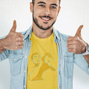 Male model wearing a yellow Nosh T-shirt featuring an abstract homoerotic graphic illustration, styled with a denim shirt and giving a thumbs-up.