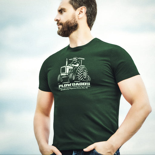 PRODUCT IMAGE: Man wearing a forest green t-shirt with a tractor graphic and 'Plow Daddy' text against a light background