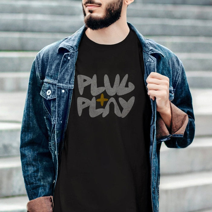 PRODUCT IMAGE: Plug + Play T-shirt | Funny, Dirty, Raunchy T-shirts for Horny Gay Guys who Play with Penis | Model wears Black V1 shirt (X-rated version) | A typographic design uses the negative space of the letter a in the shape of a cock