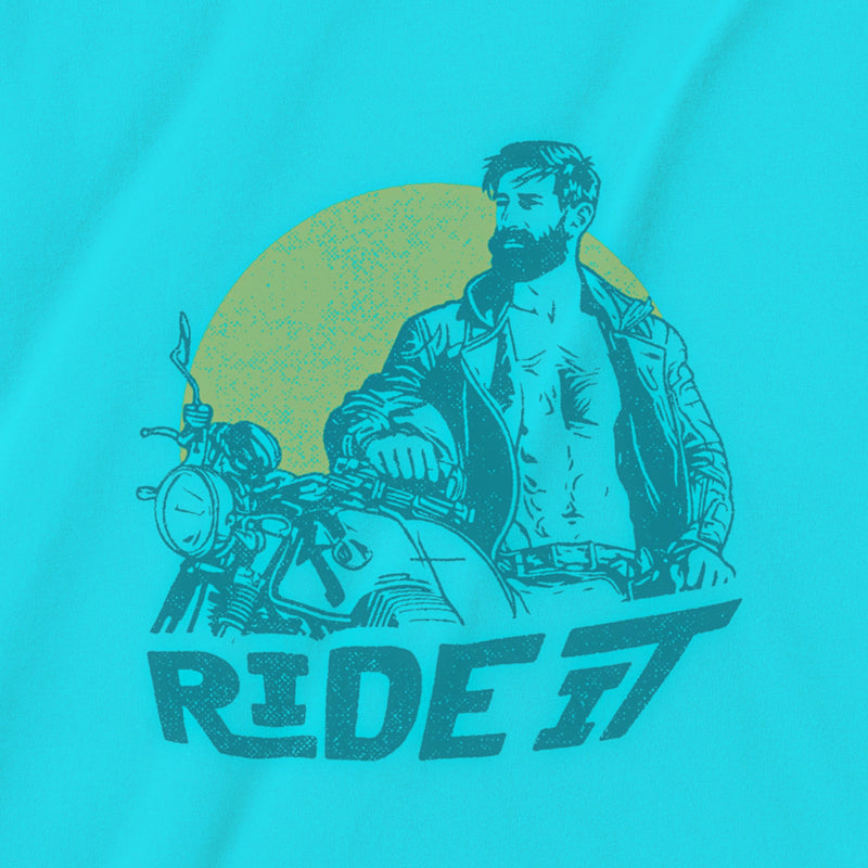 A close-up detail of the graphic printed on a turquoise tee featuring a rugged, bearded biker in a distressed vintage print style with the design's namesake, "Ride It."