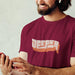 Deeper T-shirt | Raunchy Tees for Horny Gay Guys Who Like to Bang | Model wears Maroon shirt with a typographic design