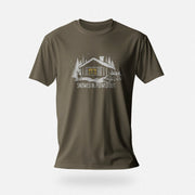 Men’s graphic t-shirt showing a snowy log cabin and plow truck, featuring the phrase “Snowed In, Plowed Out,” a subtle innuendo design for gay men. Product shot shows Army tee.